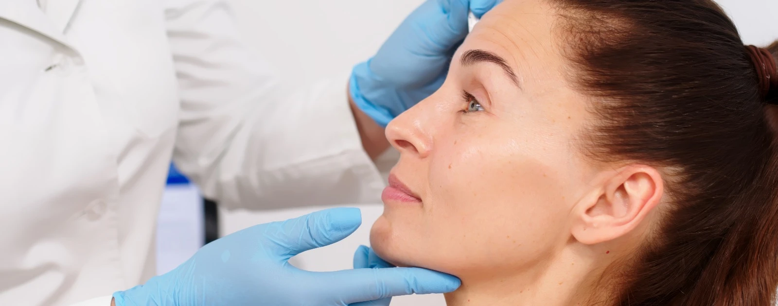 dermatologista observa rosto de paciente