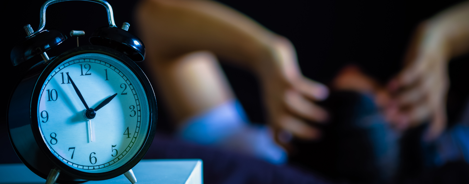 Homem com insónia com relógio em primeiro plano