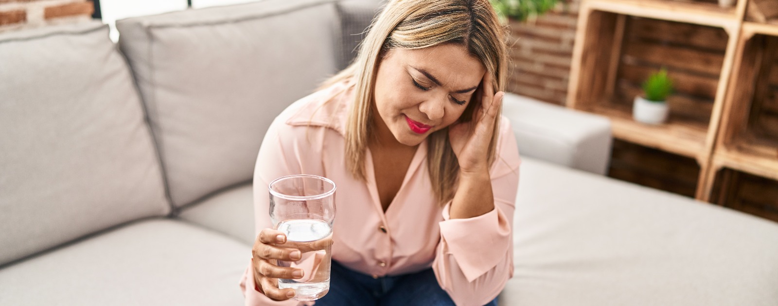 mulher a beber água para aliviar dor de cabeça