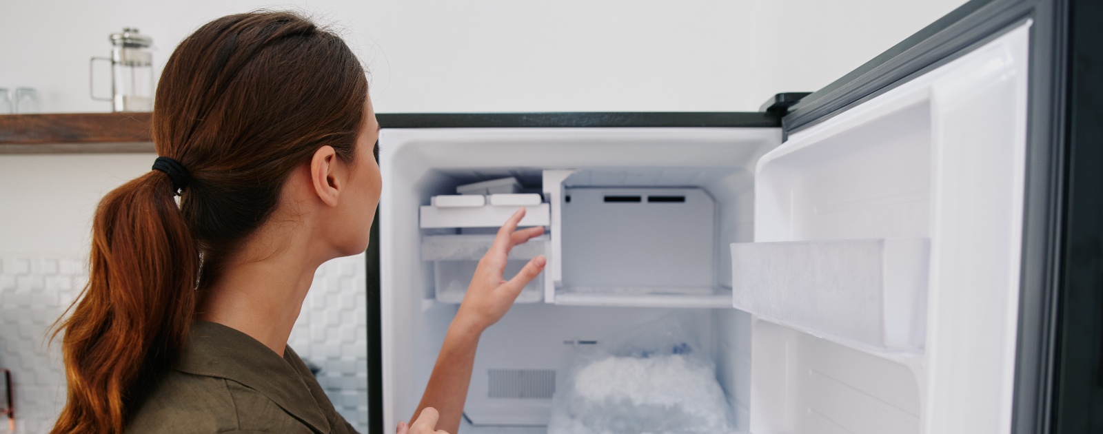 mulher a tocar no gelo do congelador