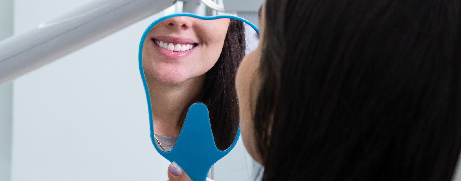 mulher a ver os dentes brancos ao espelho