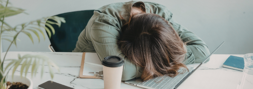 Mulher stressada com a cabeça em cima do computador