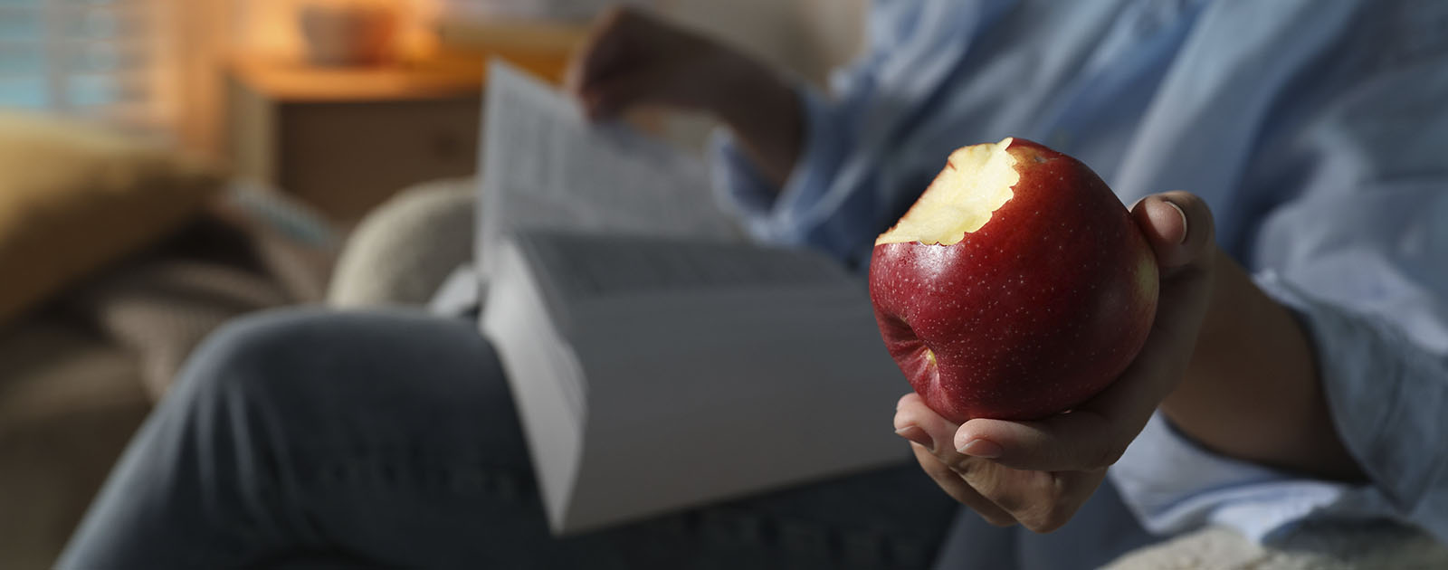 mulher sentada no sofá a comer uma maçã