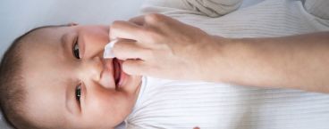 mãe a limpar a boca do bebé depois de bolçar