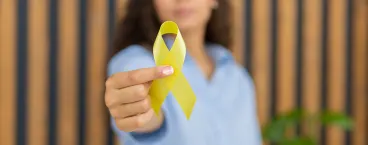 mulher a segurar laço amarelo que simboliza o sarcoma