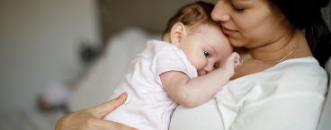 pai a segurar bebé de barriga para baixo