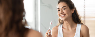 mulher jovem em frente ao espelho com escova de dentes