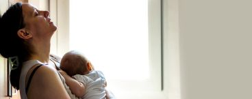 mãe com ar cansado segura bebé ao colo