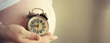 mulher grávida a segurar num relógio