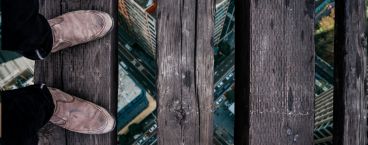 pessoa em cima de uma ponte de madeira com vertigens