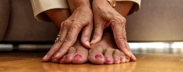 mulher sentada com mãos apoiadas nos pés