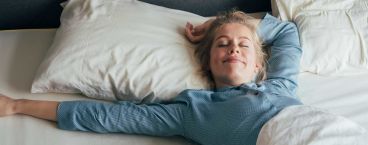 mulher sorridente deitada na cama a dormir