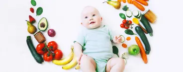 bebé rodeado de alimentos sólidos 