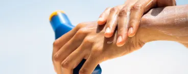mulher a aplicar protetor solar no braço