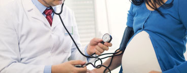 médico a medir a tensão de mulher grávida