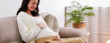 mulher grávida a sorrir sentada no sofá