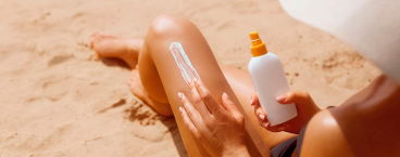 mulher a aplicar protetor solar na perna
