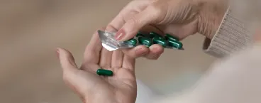 mulher a tirar medicamento da embalagem e colocar na mão