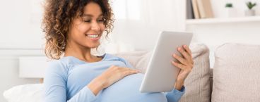 mulher grávida com mão na barriga a olhar para imagem de ecografia