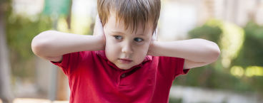 menino com síndrome de asperger a tapar os ouvidos