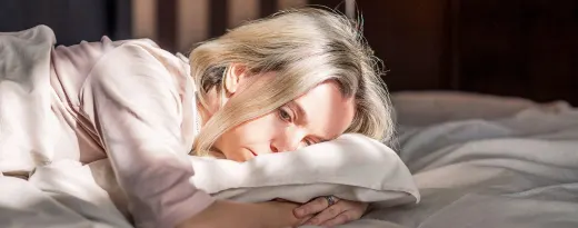 mulher deitada na cama com ar deprimido