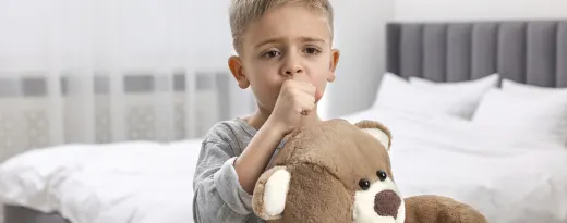 menino sentado na cama a tossir