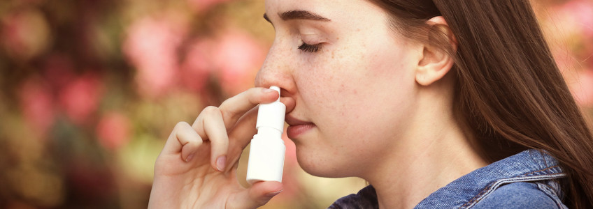 rapariga a aplicar spray nasal contra alergia