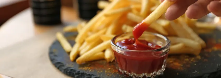 pessoa a molhar batata frita no ketchup