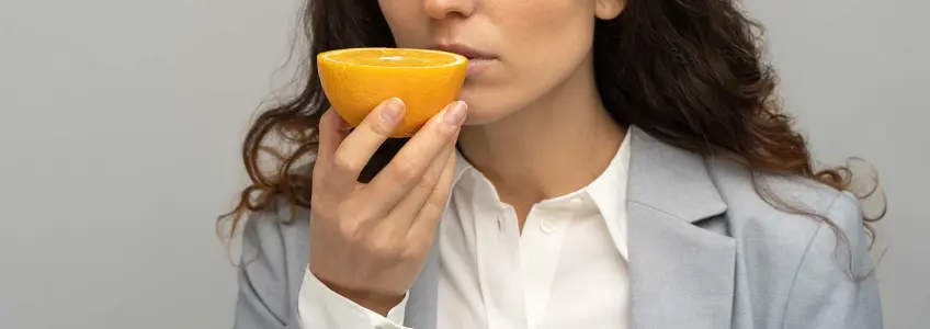 mulher a tentar cheirar uma laranja