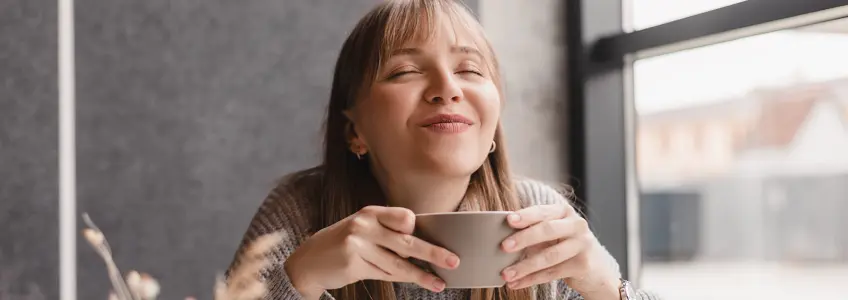 rapariga a sorrir enquanto bebe café