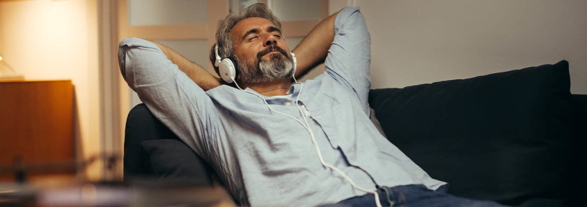 homem a ouvir música enquanto relaxa no sofá