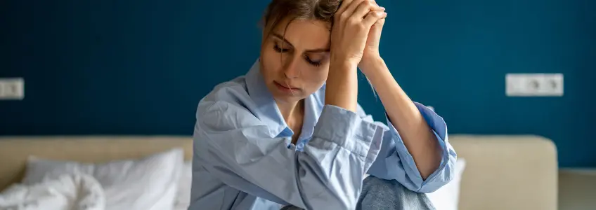 mulher sentada na cama com ar deprimido