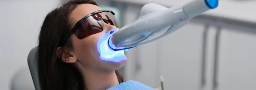 rapariga a fazer branqueamento dentário no dentista