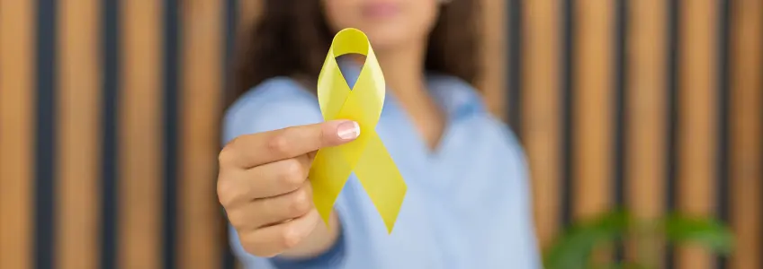 mulher a segurar laço amarelo que simboliza o sarcoma