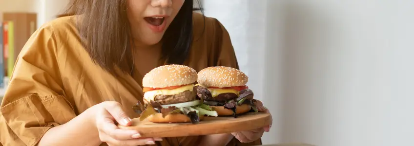 rapariga a segurar uma tábua com dois hambúrgueres