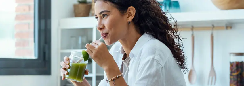 rapariga a beber um sumo de vegetais