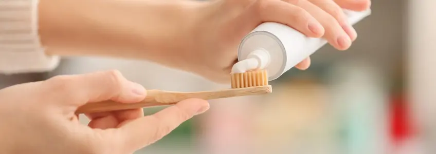 mulher a colocar pasta de dentes na escova