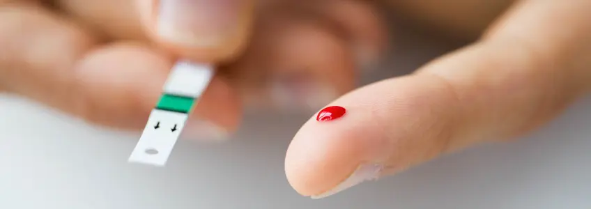 faixa de teste de glicemia e dedo com gota de sangue