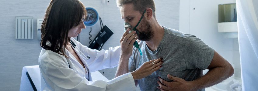 paciente homem com máscara de oxigénio a ser avaliado por médica