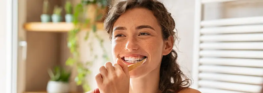 rapariga a escovar os dentes com escova manual