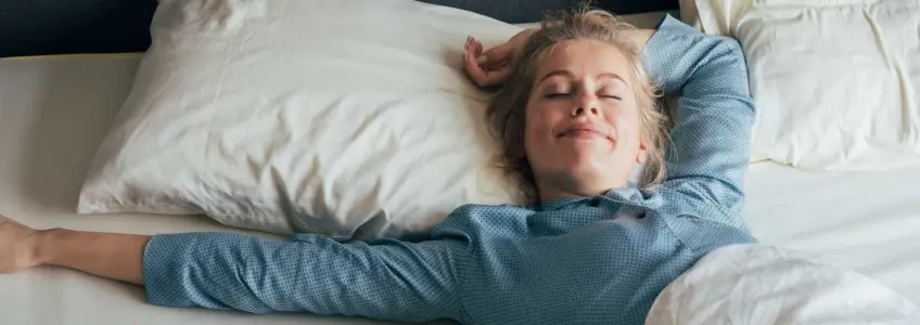 mulher sorridente deitada na cama a dormir