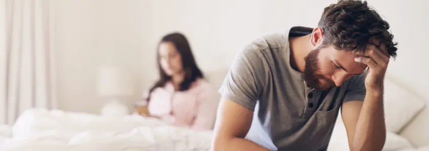 homem sentado na cama com ar desapontado