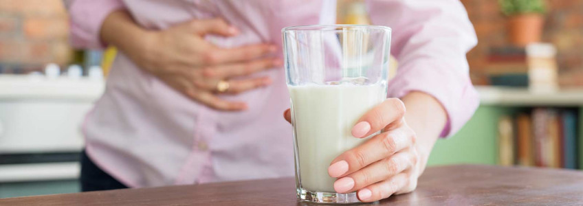 mulher com dor abdominal e um copo de leite