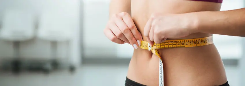 mulher a medir tamanho da cintura com fita métrica
