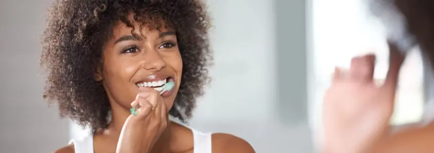 mulher a colocar pasta de dentes na escova elétrica