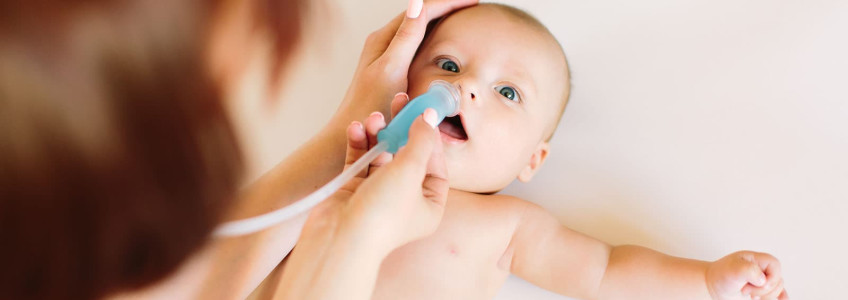 mãe a limpar o nariz do bebé com aspirador nasal