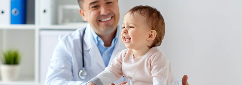 médico no consultório a olhar para bebé sorridente
