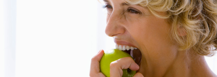 Pessoa a sorrir a comer uma maçã