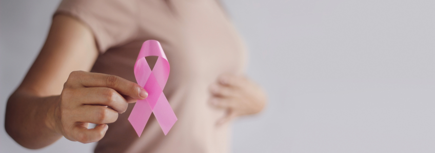 Pessoa a segurar laço com cor da luta contra o cancro da mama enquanto analisa a mama