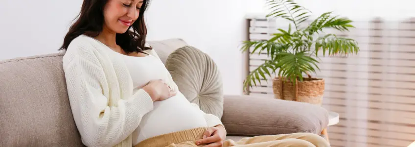 mulher grávida a sorrir sentada no sofá